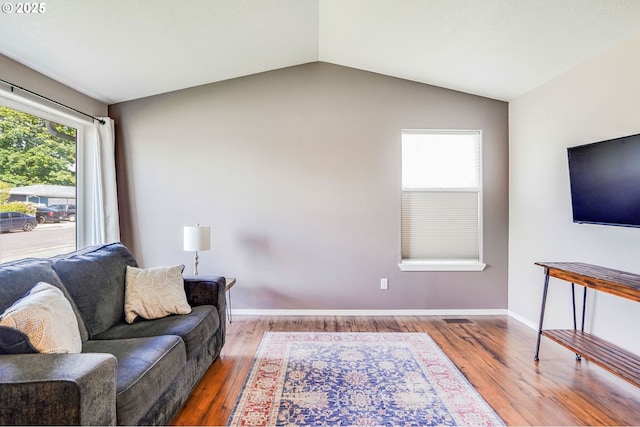 living room featuring wood finished floors, vaulted ceiling, and baseboards