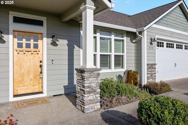 view of exterior entry featuring a shingled roof, a garage, and stone siding