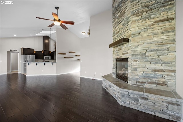 unfurnished living room with ceiling fan, high vaulted ceiling, baseboards, and dark wood-style floors