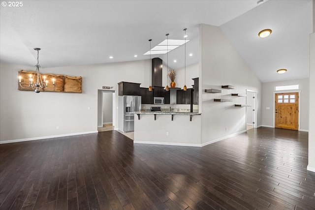 unfurnished living room featuring baseboards, high vaulted ceiling, a chandelier, and wood finished floors