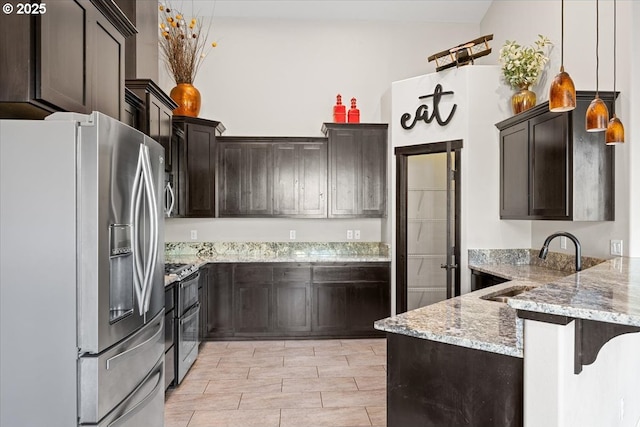 kitchen with a sink, appliances with stainless steel finishes, a peninsula, dark brown cabinetry, and light stone countertops