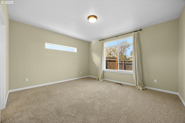 carpeted empty room featuring baseboards, visible vents, and a wealth of natural light