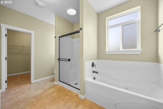 bathroom featuring a spacious closet, visible vents, a garden tub, and a stall shower