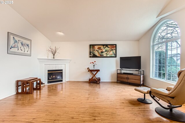 living room featuring a fireplace, vaulted ceiling, and light hardwood / wood-style floors