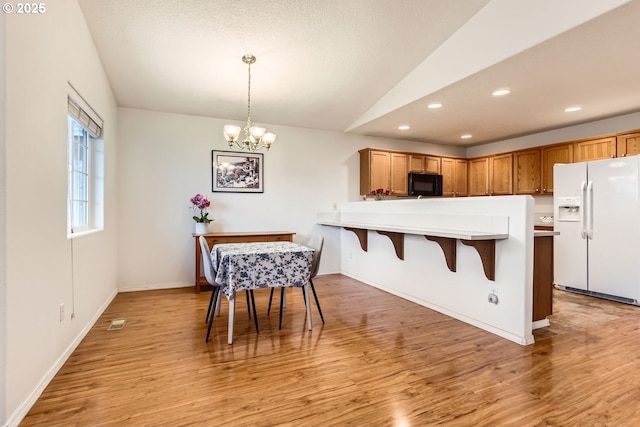 kitchen with decorative light fixtures, lofted ceiling, a chandelier, white fridge with ice dispenser, and light hardwood / wood-style floors