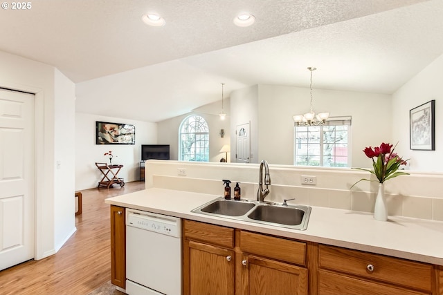 kitchen featuring sink, hanging light fixtures, white dishwasher, a notable chandelier, and vaulted ceiling