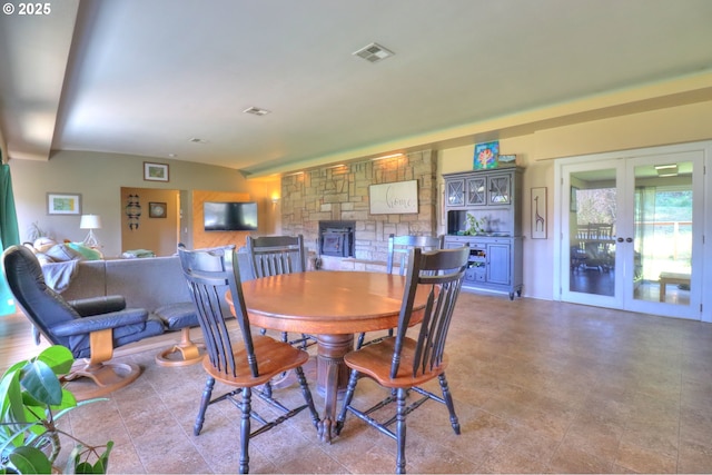 dining space with lofted ceiling, french doors, a fireplace, and visible vents