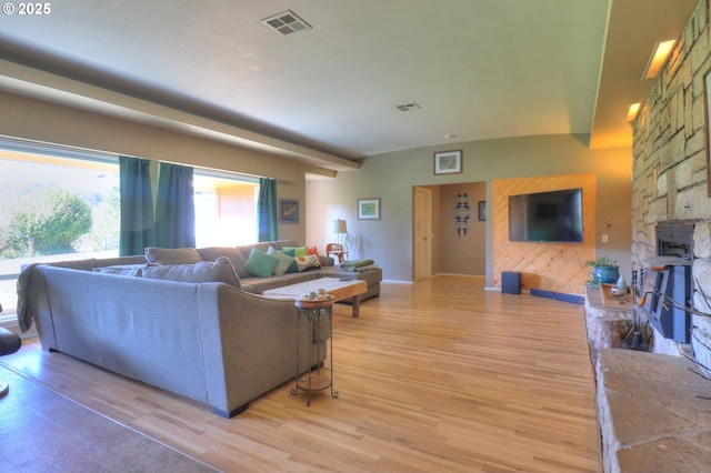 living room featuring light wood finished floors, a fireplace, visible vents, and baseboards