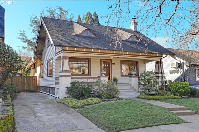 view of front of property featuring a porch, fence, a front lawn, and a chimney