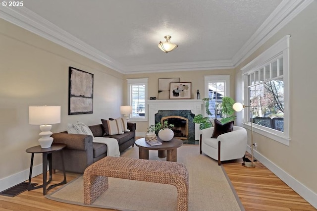 living room featuring a premium fireplace, baseboards, crown molding, and light wood finished floors