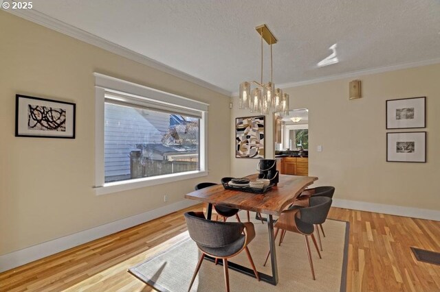 dining area with light wood-style flooring, visible vents, and ornamental molding