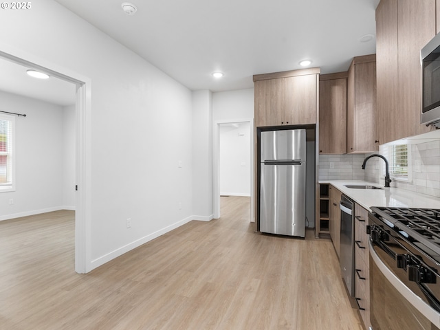 kitchen featuring tasteful backsplash, appliances with stainless steel finishes, sink, and light wood-type flooring