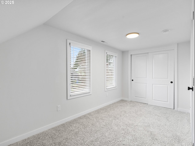 unfurnished bedroom with lofted ceiling, carpet flooring, and a closet