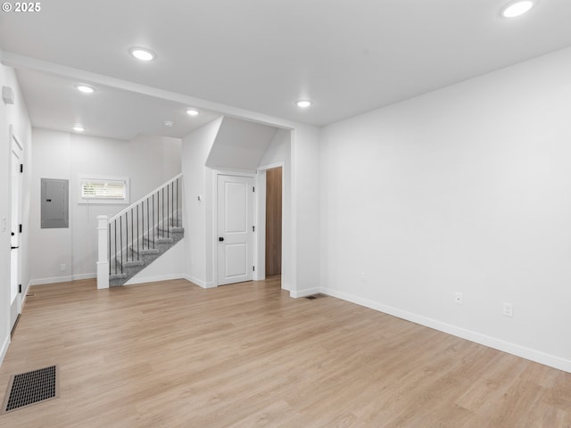 unfurnished room with electric panel and light hardwood / wood-style floors