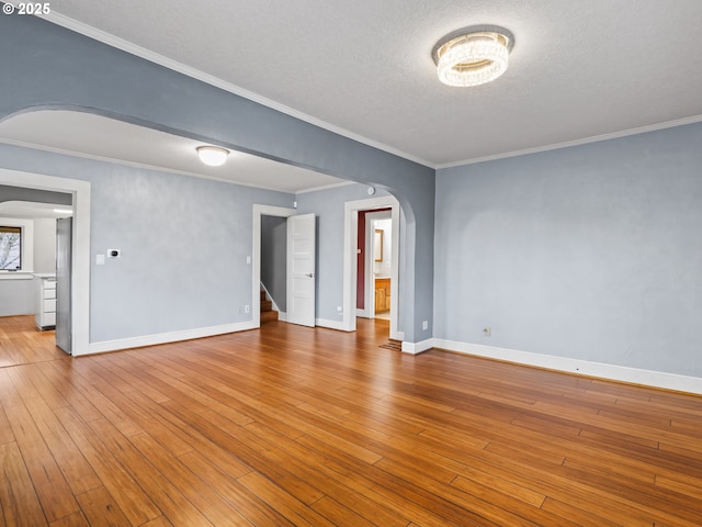 spare room with ornamental molding, a textured ceiling, and light hardwood / wood-style floors