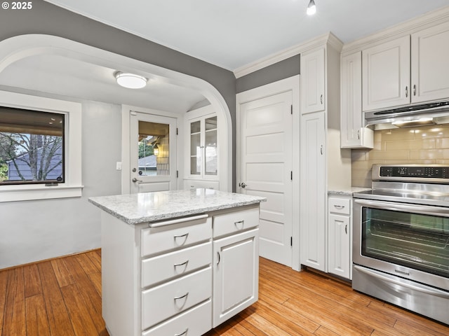 kitchen with white cabinets, electric stove, decorative backsplash, and a center island