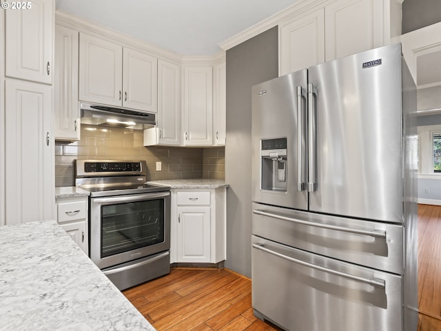 kitchen featuring light stone countertops, stainless steel appliances, light hardwood / wood-style floors, backsplash, and white cabinetry