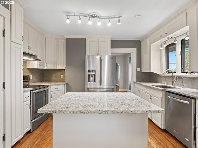 kitchen with appliances with stainless steel finishes, white cabinets, light hardwood / wood-style floors, and a center island