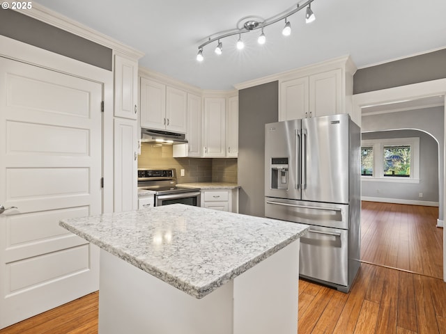 kitchen featuring a kitchen island, stainless steel appliances, tasteful backsplash, and white cabinetry