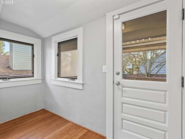 doorway to outside with hardwood / wood-style floors, vaulted ceiling, and plenty of natural light