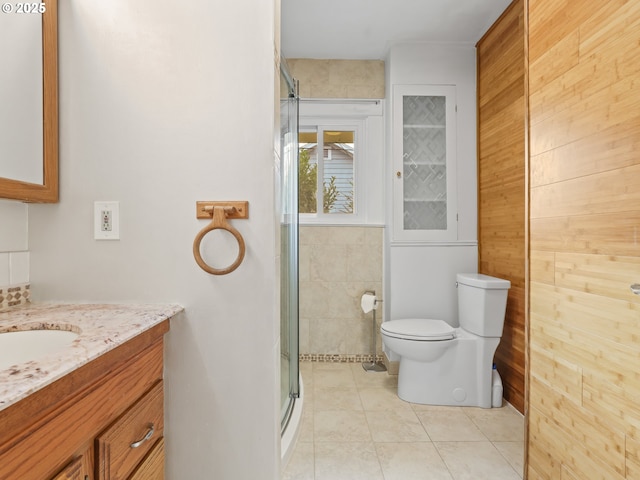 bathroom featuring toilet, wood walls, tile patterned floors, an enclosed shower, and vanity