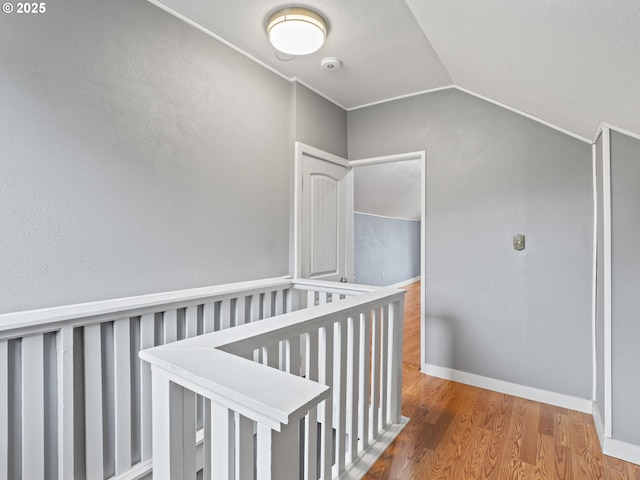 corridor with vaulted ceiling and hardwood / wood-style floors