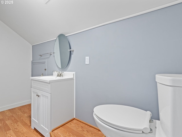 bathroom featuring toilet, wood-type flooring, vanity, and vaulted ceiling