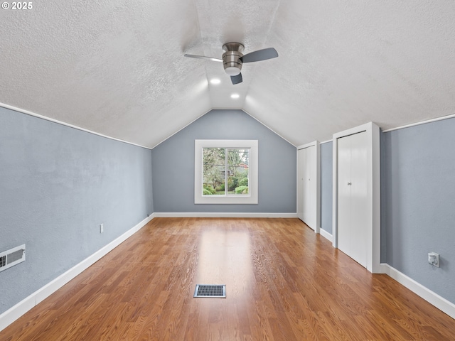 additional living space featuring a textured ceiling, ceiling fan, vaulted ceiling, and wood-type flooring