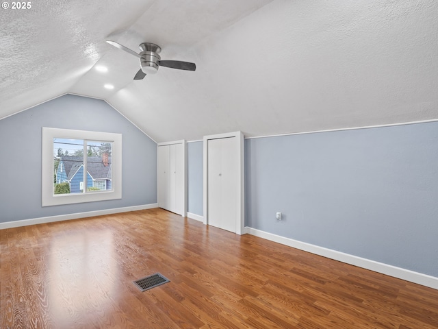 bonus room with lofted ceiling, wood-type flooring, a textured ceiling, and ceiling fan