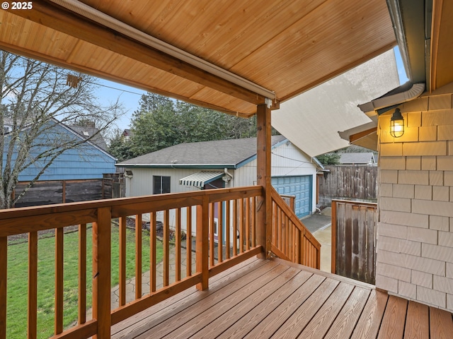 wooden deck with a garage, an outbuilding, and a lawn