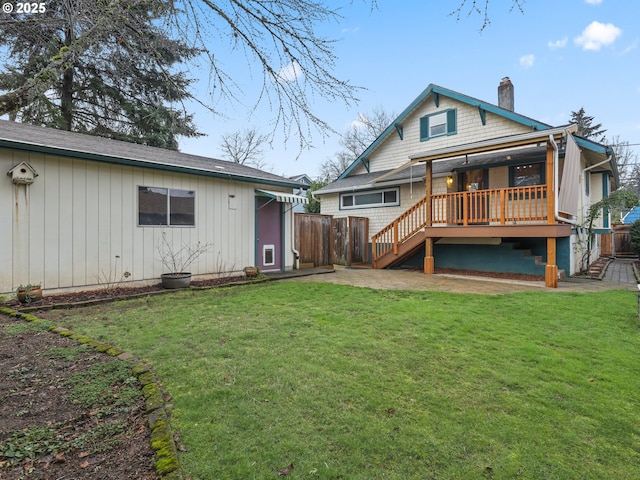 rear view of house featuring a wooden deck and a lawn