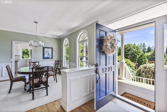1221 SW Forest Meadows Way, Lake Oswego, OR 97034 - entrance foyer with ornamental molding, light wood finished floors, a chandelier, healthy amount of natural light, and a wainscoted wall