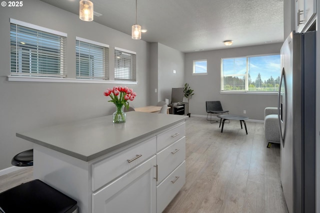 kitchen with freestanding refrigerator, white cabinetry, baseboards, and light wood-type flooring