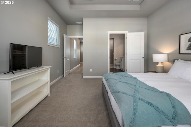 bedroom featuring visible vents, baseboards, ensuite bathroom, a tray ceiling, and carpet