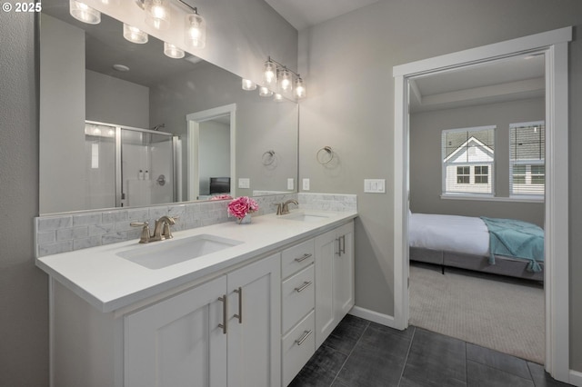 ensuite bathroom with double vanity, a sink, baseboards, and a stall shower