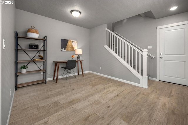 office area with a textured ceiling, baseboards, and wood finished floors