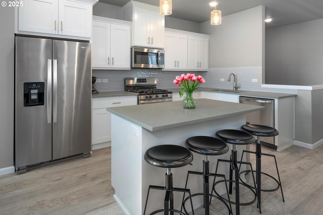 kitchen featuring a sink, appliances with stainless steel finishes, light wood-style flooring, and white cabinetry