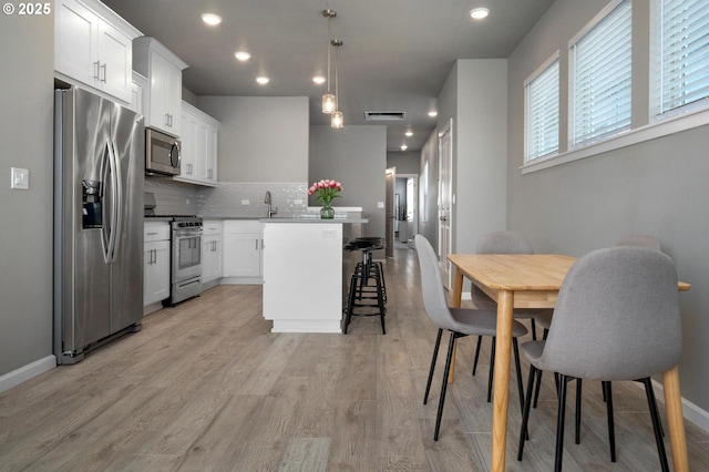 kitchen with backsplash, visible vents, appliances with stainless steel finishes, a center island, and a sink