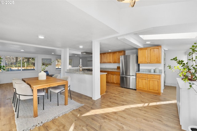 kitchen featuring stainless steel refrigerator, kitchen peninsula, and light hardwood / wood-style floors