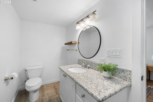 bathroom featuring vanity, wood-type flooring, and toilet