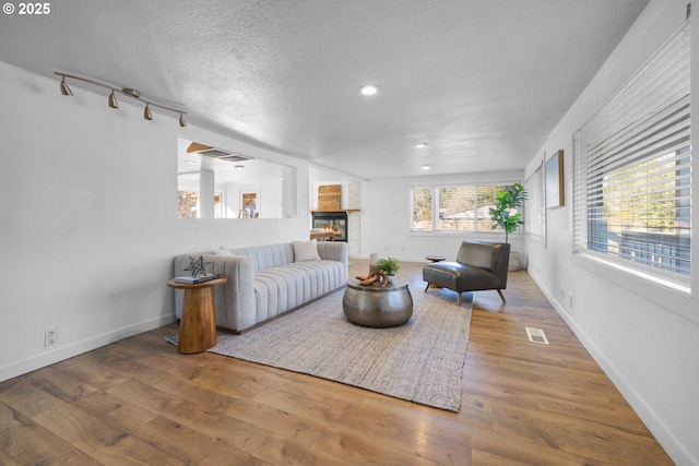 living room featuring a large fireplace, hardwood / wood-style floors, and a textured ceiling