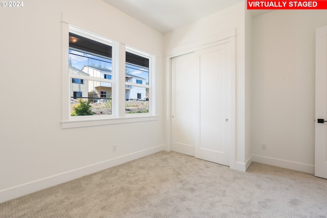 unfurnished bedroom with a closet, light carpet, and baseboards