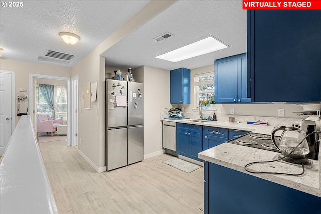 15707 NE Beech St, Portland, OR 97230 - kitchen with appliances with stainless steel finishes, blue cabinetry, a textured ceiling, light wood-type flooring, and light countertops
