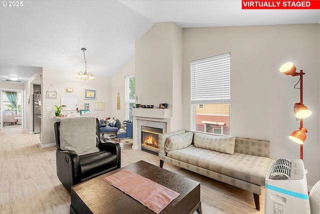 15707 NE Beech St, Portland, OR 97230 - living area featuring light wood-style floors, lofted ceiling, a tiled fireplace, plenty of natural light, and a chandelier