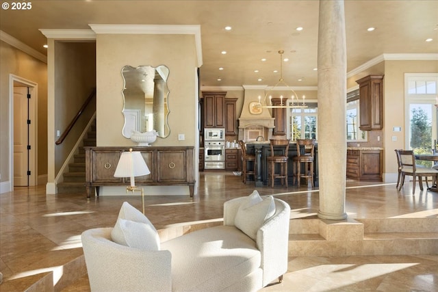 living room with crown molding, decorative columns, and a notable chandelier