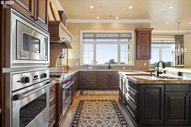 kitchen with sink, light tile patterned floors, crown molding, appliances with stainless steel finishes, and light stone counters