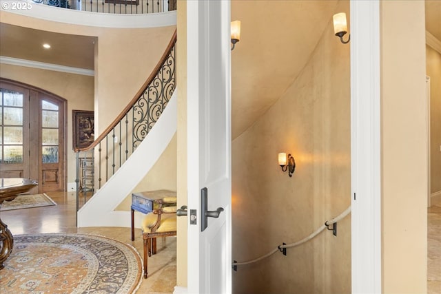 stairway featuring ornamental molding, french doors, and a high ceiling