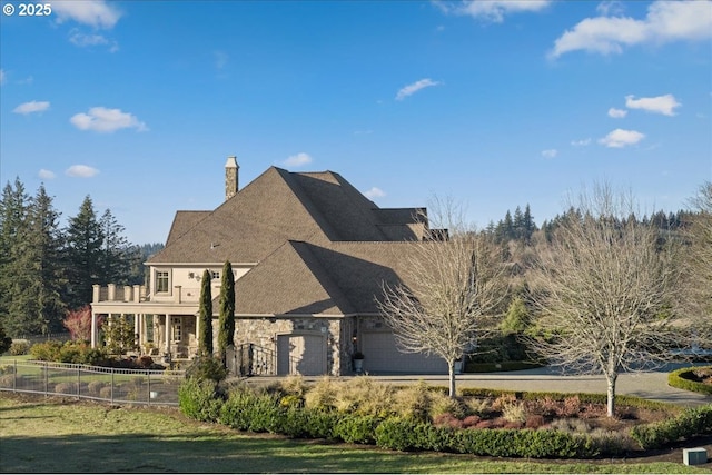12955 NW Skyline Blvd, Portland, OR 97231 - view of front of home featuring fence, a chimney, an attached garage, a balcony, and stone siding