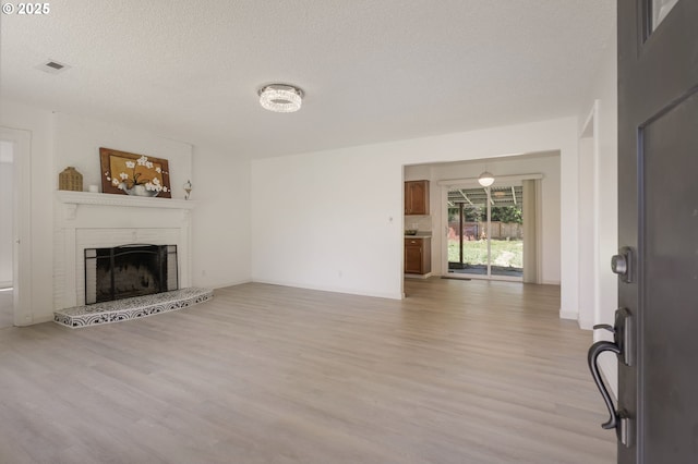 6139 SE 103rd Ave, Portland, OR 97266 - unfurnished living room with light wood finished floors, a fireplace with raised hearth, and a textured ceiling