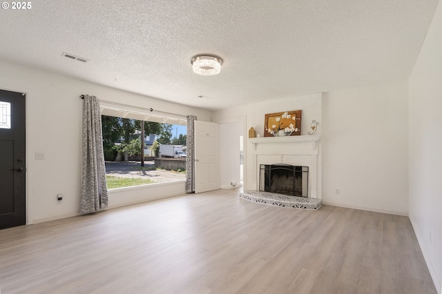6139 SE 103rd Ave, Portland, OR 97266 - unfurnished living room featuring wood finished floors, a textured ceiling, and a brick fireplace